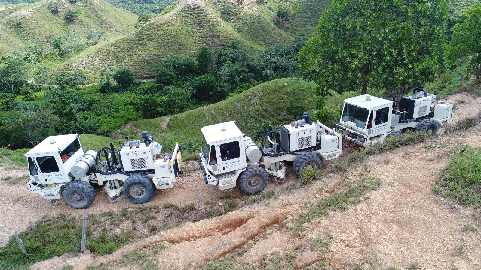 Convoy de camiones vibradores UNIVIB avanzando por trochas en las colinas del piedemonte colombiano